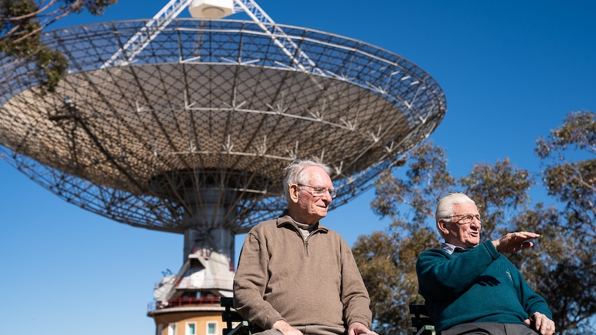 Two elderly men sitting near Parkes Observatory with the dish in the background