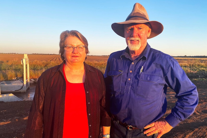 A woman and man stand on a field.