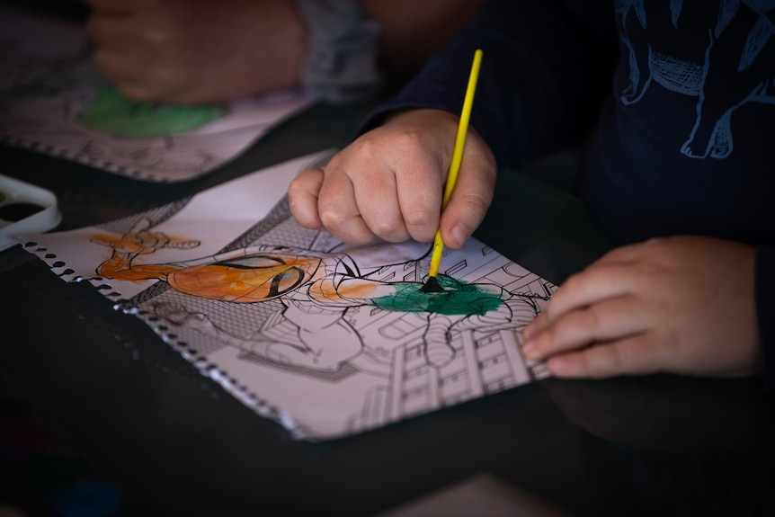 A young boy colours in a drawing 