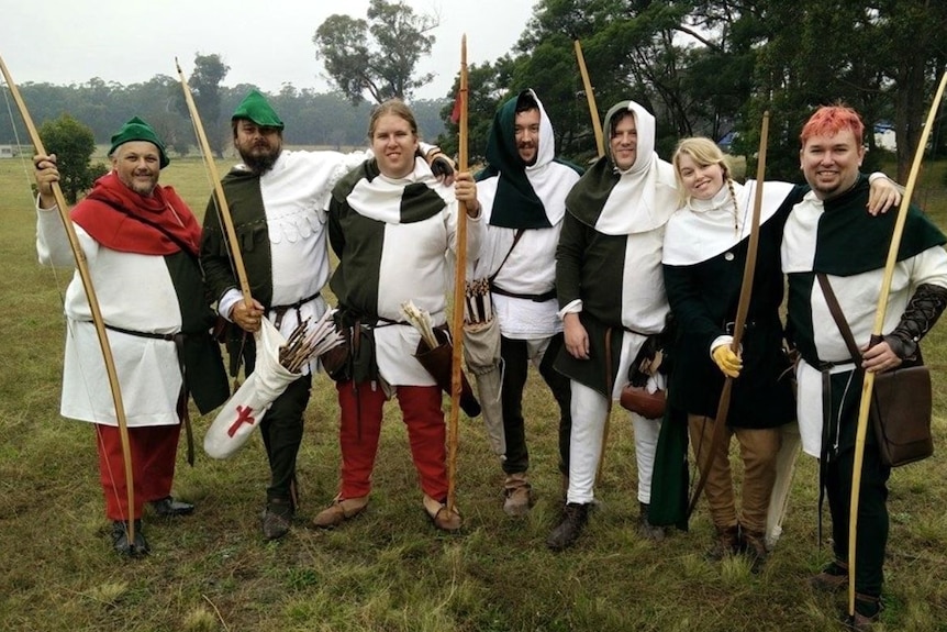 A group of men and women dressed in medieval outfits holding large bows and arrows