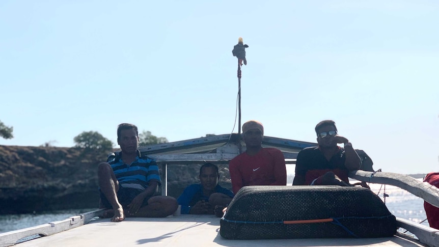 four men watch the horizon on a boat
