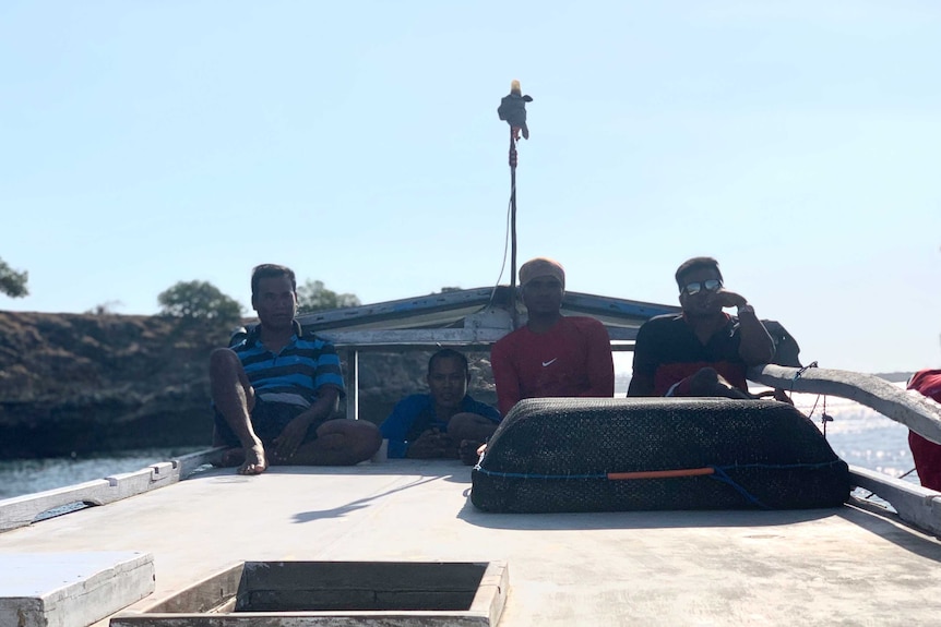 four men watch the horizon on a boat