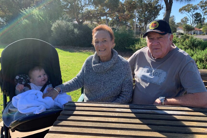 Ursula Steinberner and Leon Sharp sitting at a park table with one of their grandchildren in a pram.