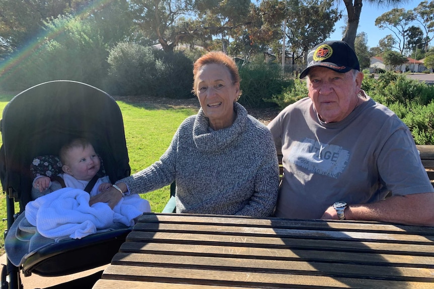 Ursula Steinberner and Leon Sharp sitting at a park table with one of their grandchildren in a pram.