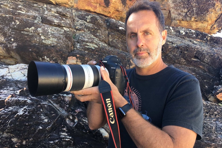 Wildlife photographer Sean Scott holds a camera.