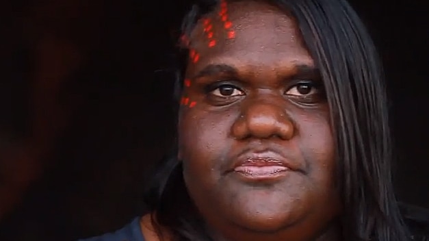 An Indigenous woman with red spots pained on one side of her face.