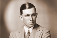 Old black and white posed photograph of a young, dark-haired man in a light-coloured suit