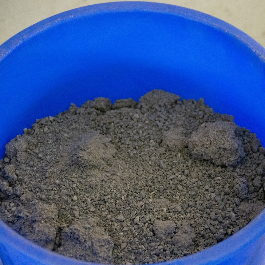 A blue bucket full of a loose gravel-like material.