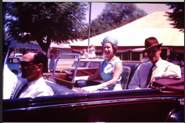 La reine et le duc d'Édimbourg assis dans une voiture à toit ouvert.