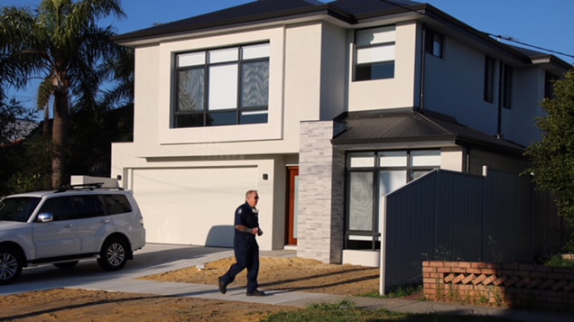 A police officer walks past a house in Mount Hawthorn with a white four-wheel drive in the driveway.