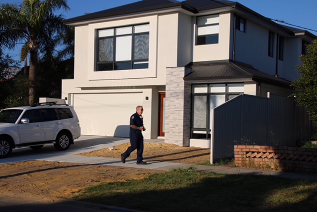A police officer walks past a house in Mount Hawthorn with a white four-wheel drive in the driveway.