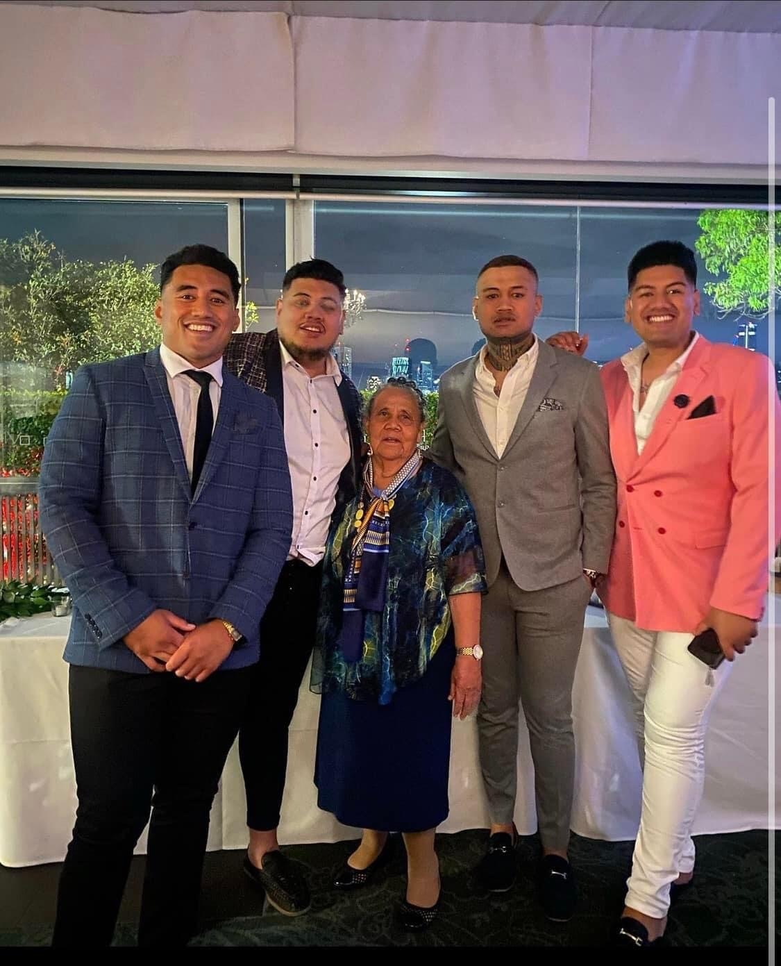 A family photo of four young men and an older woman smiling