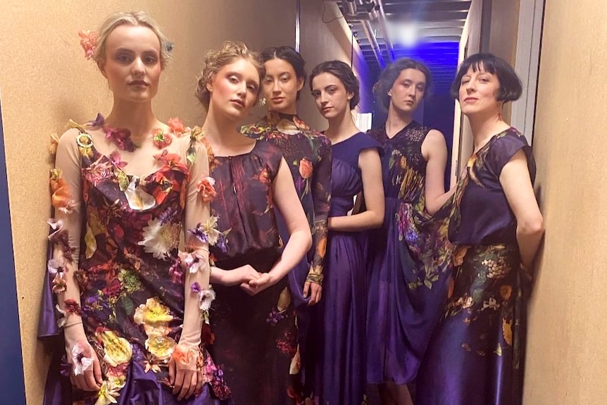 Five models stand wearing floral dresses alongside designer Sonia Heap, wearing a matching dress.