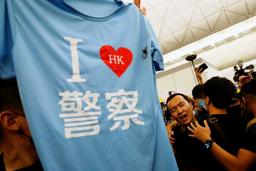 A blue t-shirt with "I Love Hong Kong Police" written in Cantonese is held up to a group of people