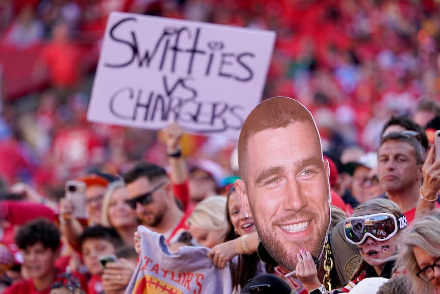 Fans hold up a sign saying Swifties vs Chargers