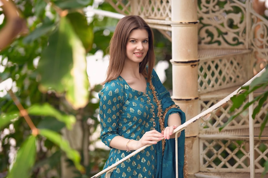 A woman poses in a teal traditional Indian suit