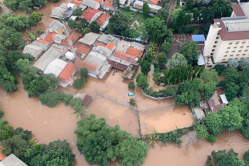 An aerial view shows roofs of homes and cars inundated by muddy water in floods.
