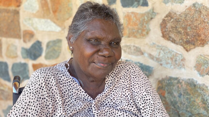 An Aboriginal woman in front of a brick wall