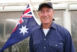 A close up shot of Fraser Anning with an Australian flag in the background