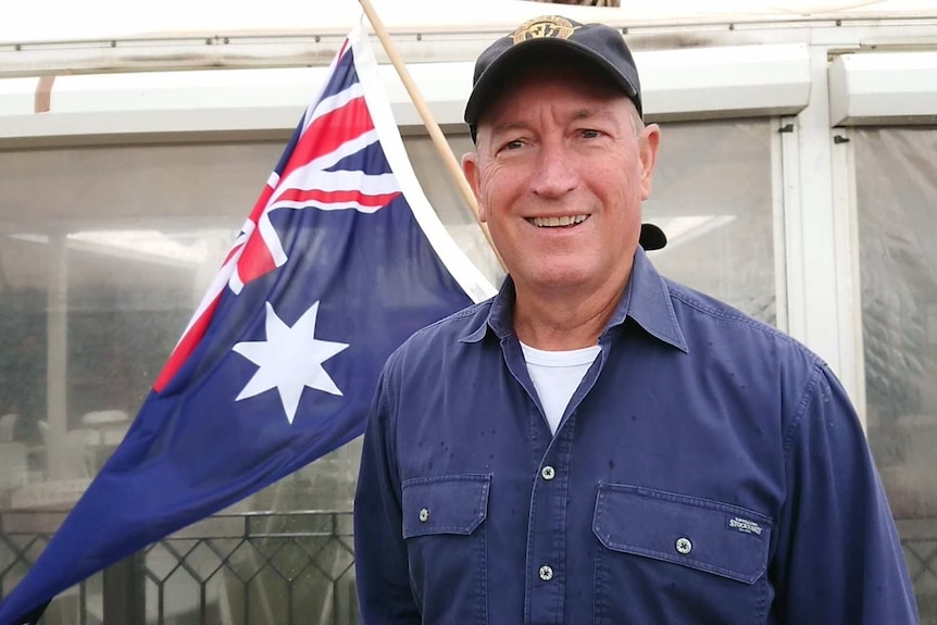 A close up shot of Fraser Anning with an Australian flag in the background