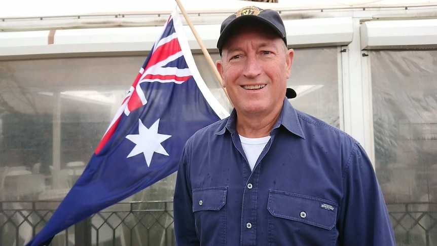 A close up shot of Fraser Anning with an Australian flag in the background
