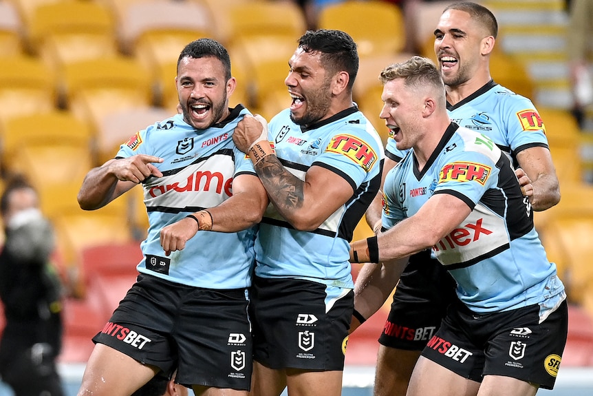 Four Cronulla Sharks NRL players celebrate a try against the Brisbane Broncos.