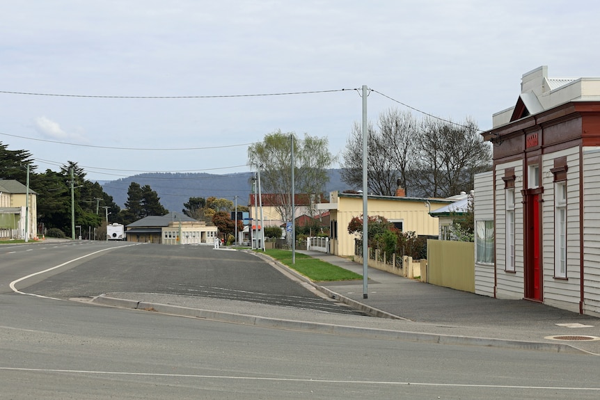 A street is empty, with houses and a shopfront by the side.
