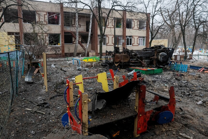 A playground with a multi-coloured play set, destroyed amongst debris from a missile strike