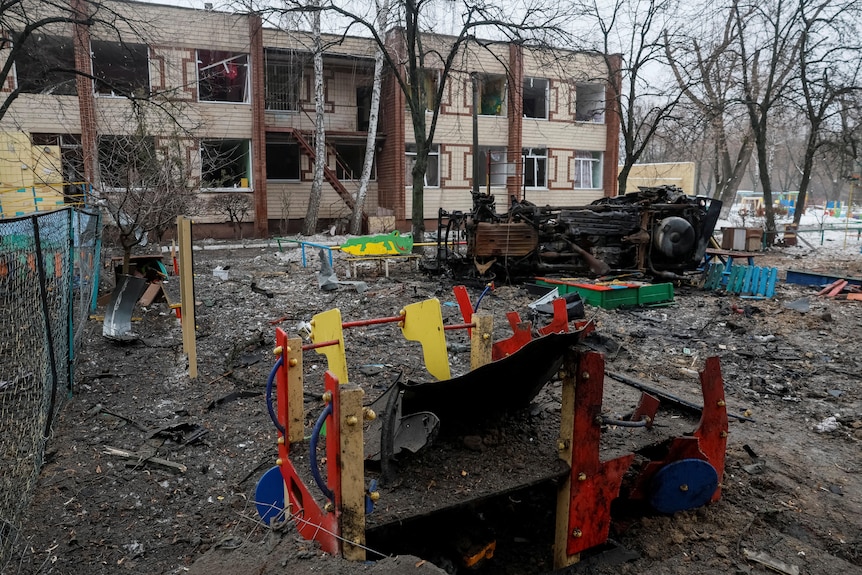 A playground with a multi-coloured play set, destroyed amongst debris from a missile strike