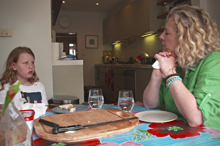 Mother and daughter sitting at a dining table.