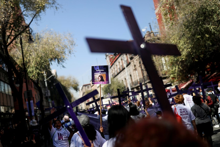 Women march holding crosses.