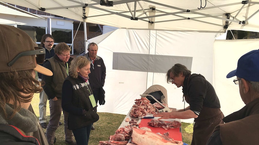 Butcher cuts up carcass as graziers look on at the Western Landcare Forum in Broken Hill in far west NSW.