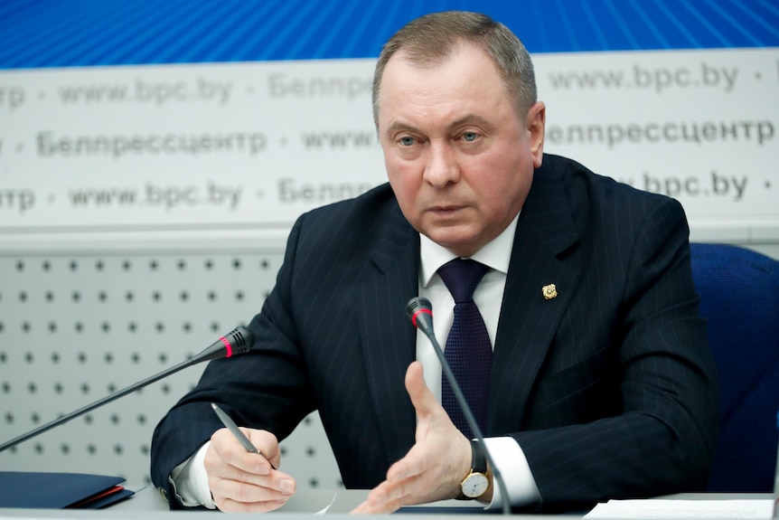 Vladimir Makei seated in front of microphones