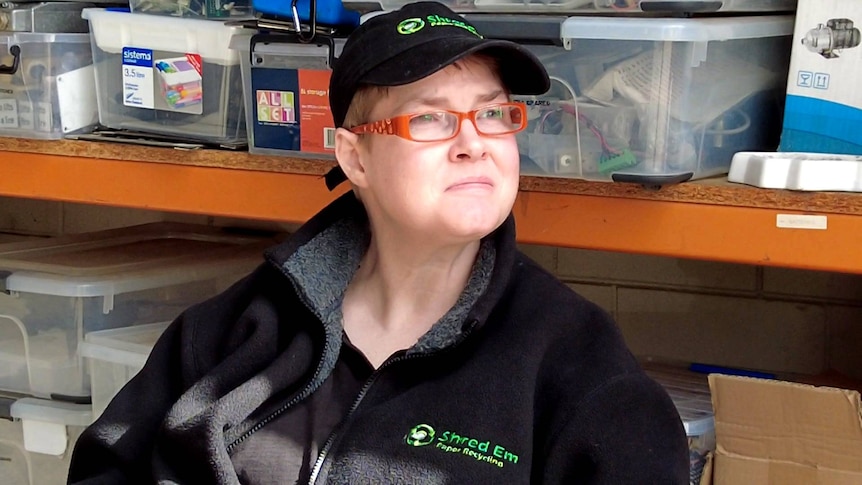 A woman wearing glasses and a cap looks to the side.