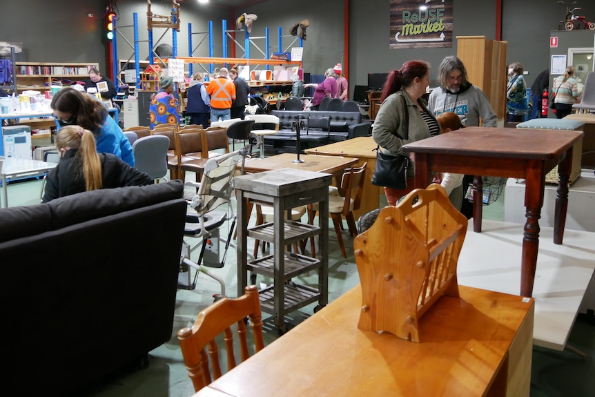 A wideshot of the Mount Gambier Reuse Market. Various tables and furniture with a number of people browsing.