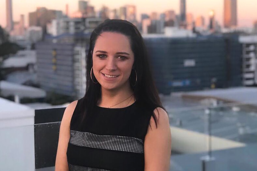 A woman standing atop a city building at dusk