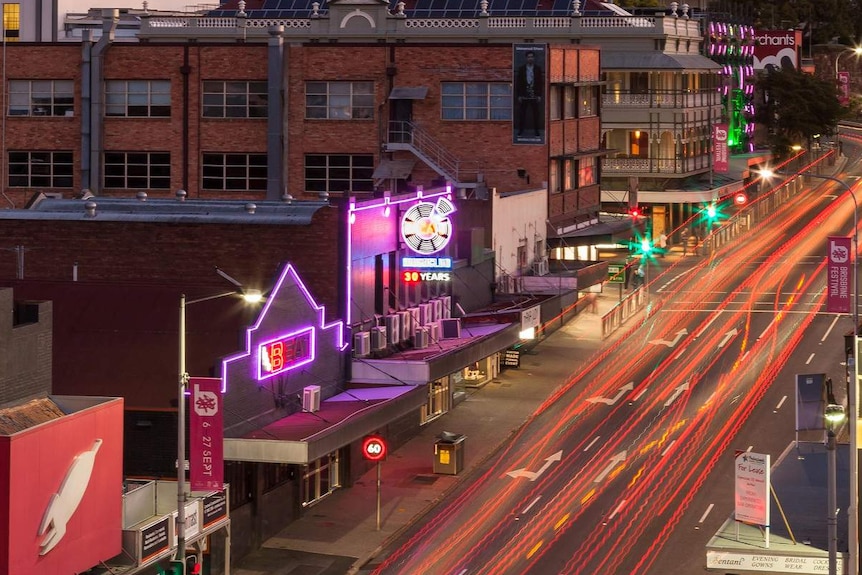 A timelapse photo of a busy street with nightclubs and colourful neon signs.
