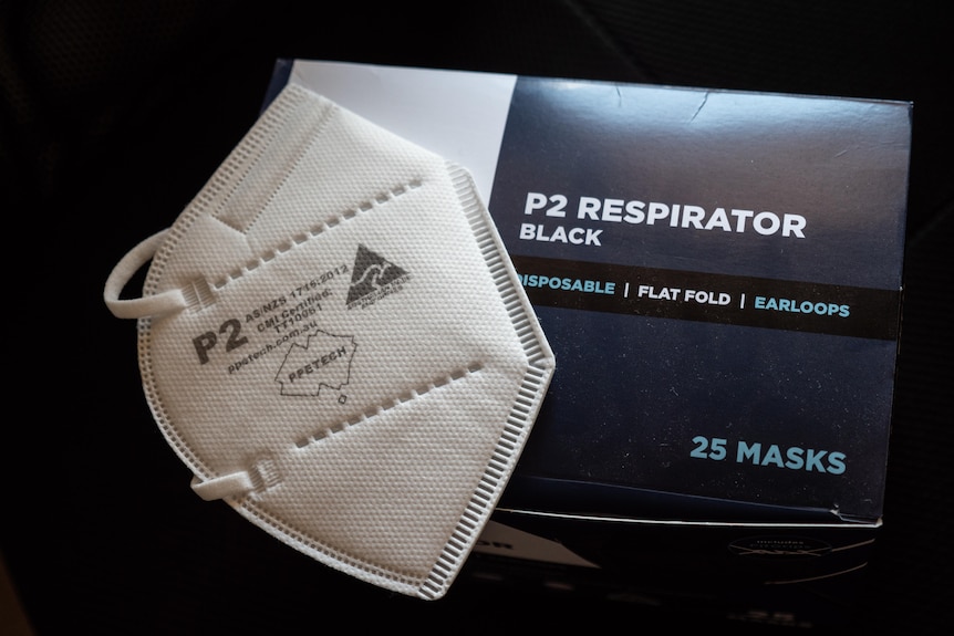 A white PM2 mask sitting on top of a box of masks