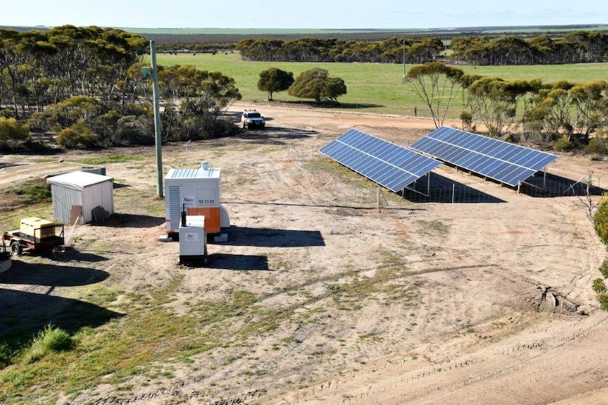 Two solar panels on the farm, with green fields in the background.