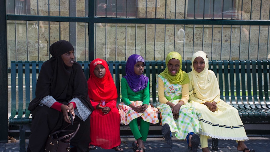 Migrants at a bus stop in Hobart.