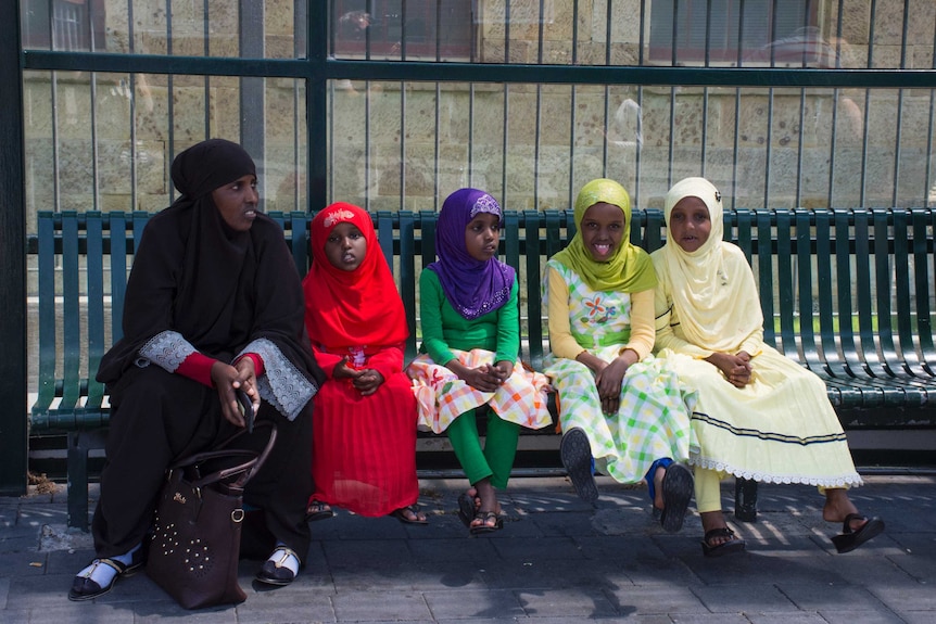 Migrants at a bus stop in Hobart.