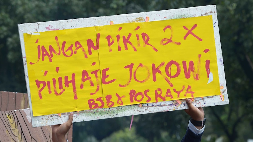 A supporter of Joko Widodo holds a banner: "Do not think twice, just vote Jokowi."