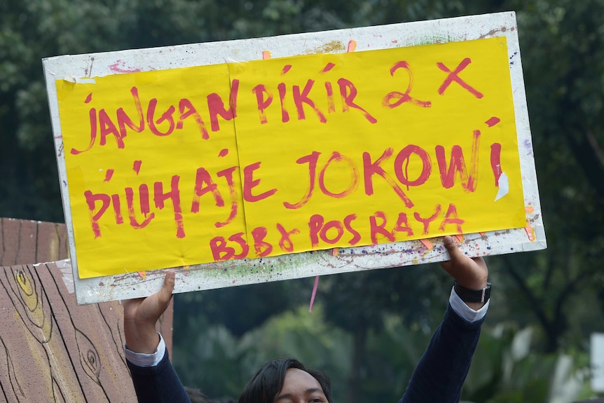 A supporter of Joko Widodo holds a banner: "Do not think twice, just vote Jokowi."