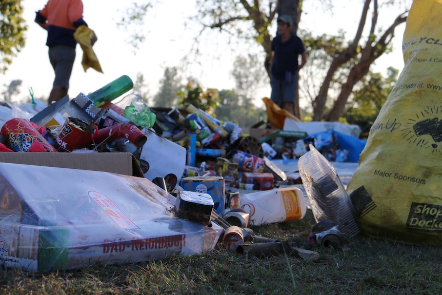 Piles of rubbish sits in boxes, along with a yellow bag with 'clean up' written on it