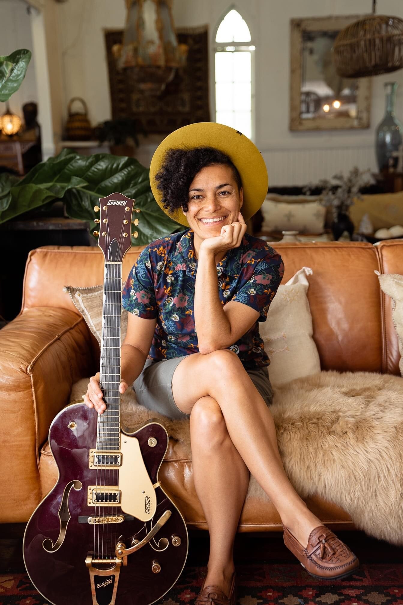 Andrea Kirwin sitzt mit Gitarre und lächelt