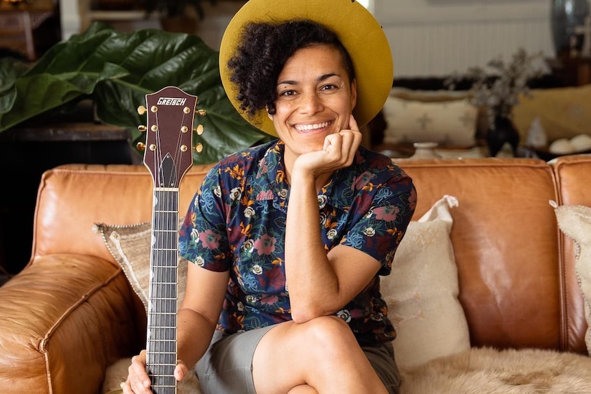 woman sitting with guitar, smiling