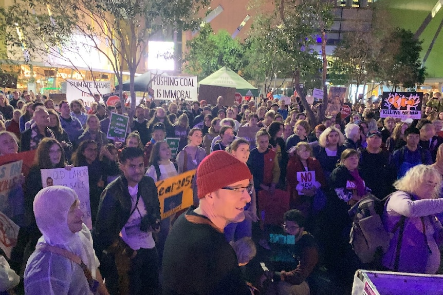 Hundreds of people holding anti-Adani placards gather in Brisbane Square.