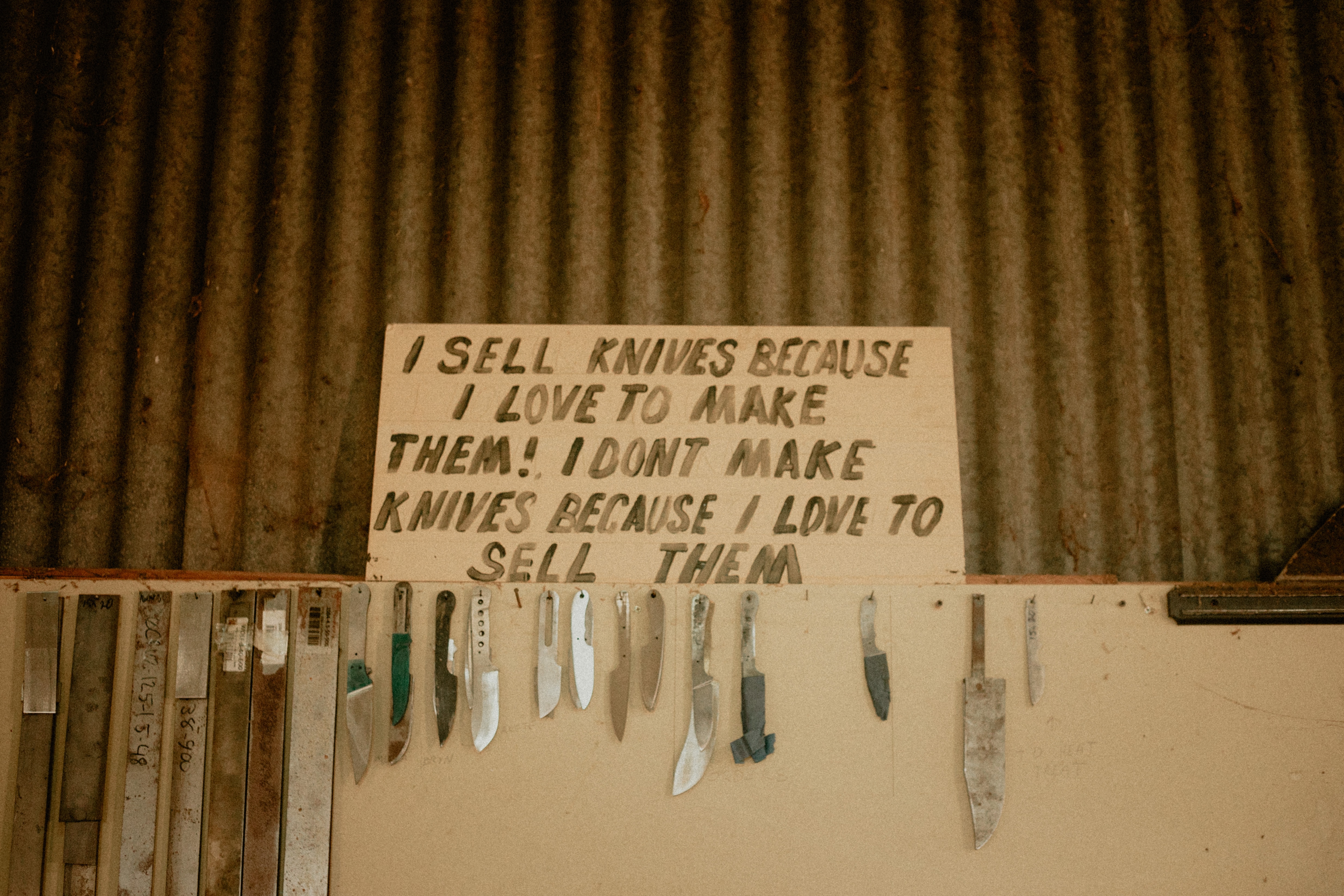 A sign reads reads "I sell knives because I love them! I don't make knives because I love to sell them" 