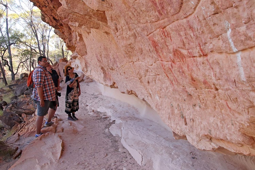 Visitors examine the art on the cliffs at Turraburra in western Queensland