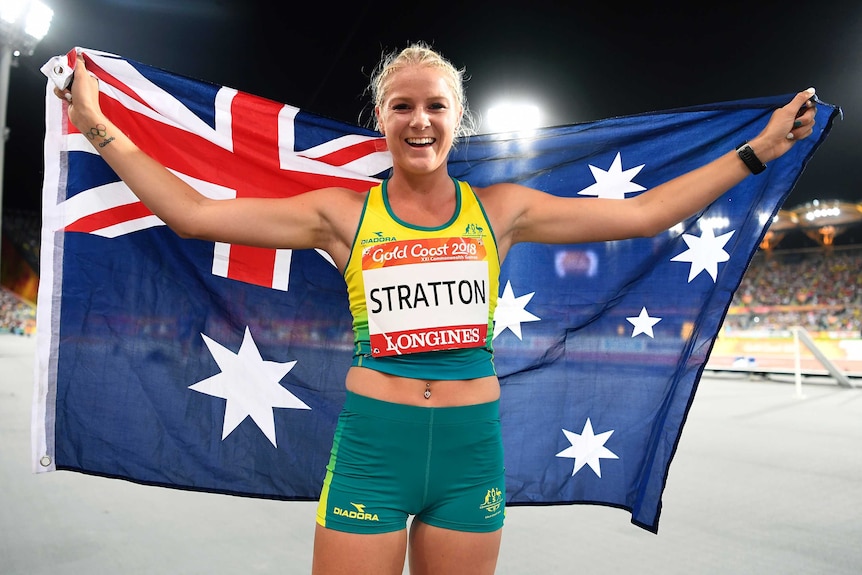 Long jumper Brooke Stratton holds Australian flag behind her head to celebrate winning a silver medal